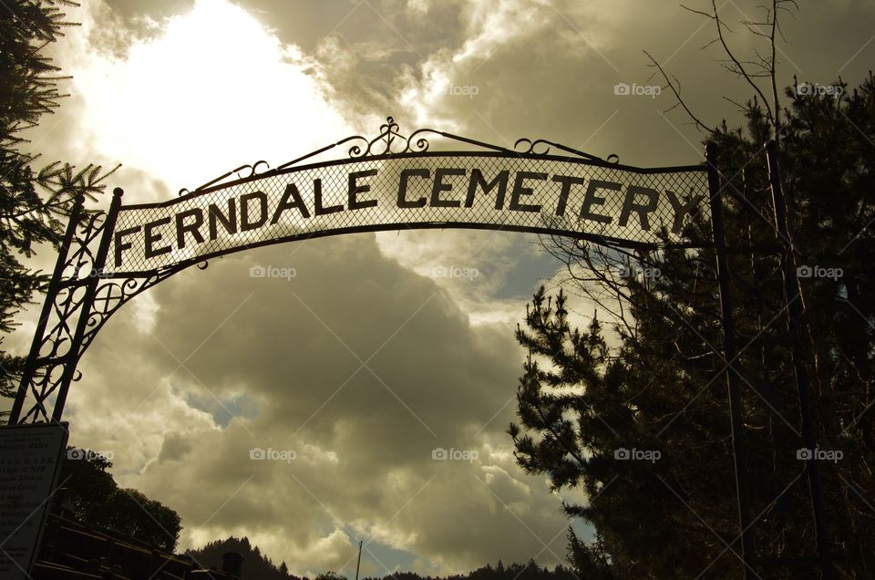 Exterior daylight.  Ferndale, WA, USA.   Dark clouds loom over the cemetery’s sign.
