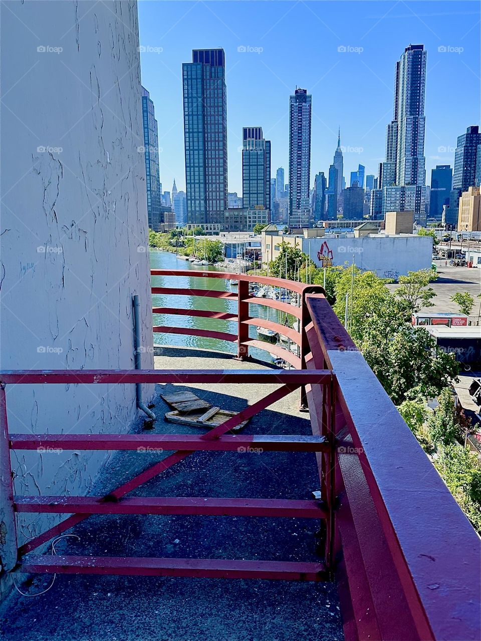 This is the center outpost of the “Pulaski Bridge” at “Newtown Creek” that connects “Greenpoint”, Bklyn to LIC, Queens overlooking the “East River”. In the distance we see “Manhattan” including the “Empire State Building”. 2024. Hypnotic Productions