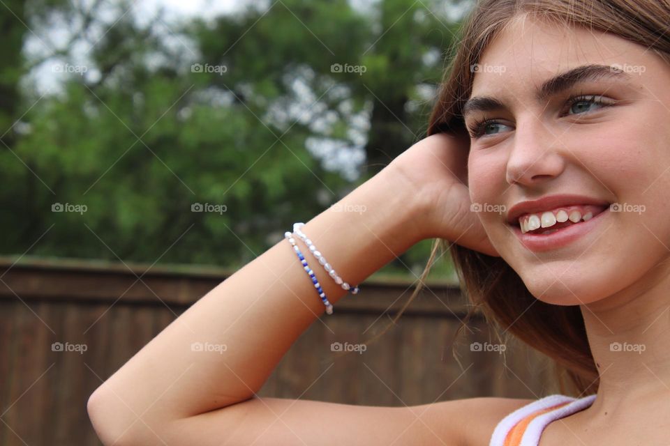 Female teenager in orange tank shirt wearing bracelet