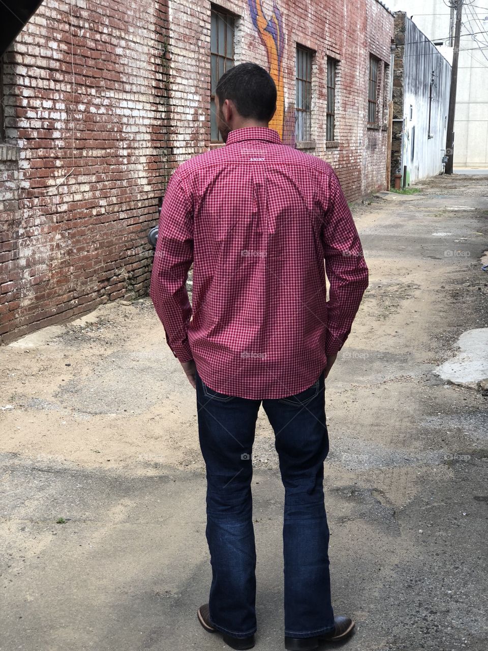 Male model showcasing clothing for a hometown clothing store features a dark wash jean and red button down.