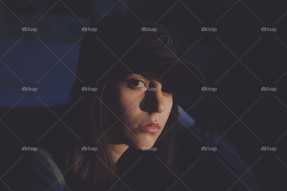 A young woman in sunset rays in a dark room