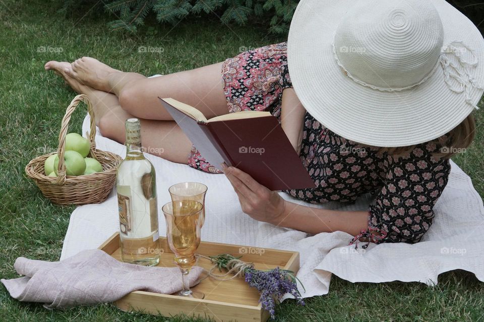 Picnic, a woman reading a book in the park on the ground 
