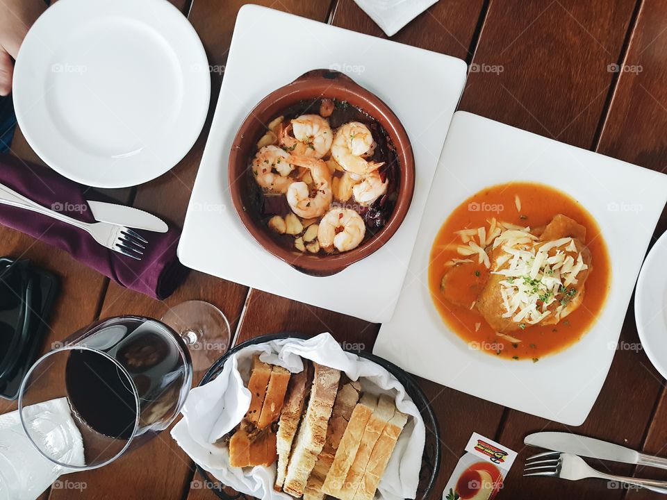 Wine, shrimp, breads and fresh eggplant flatly