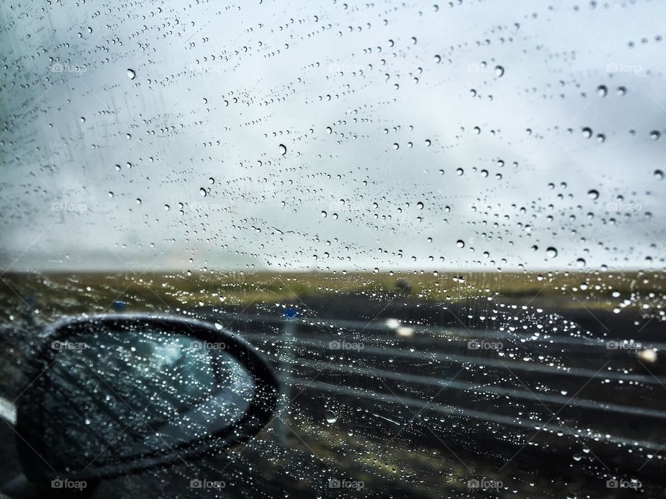 Raindrop on car window with side-view-mirror