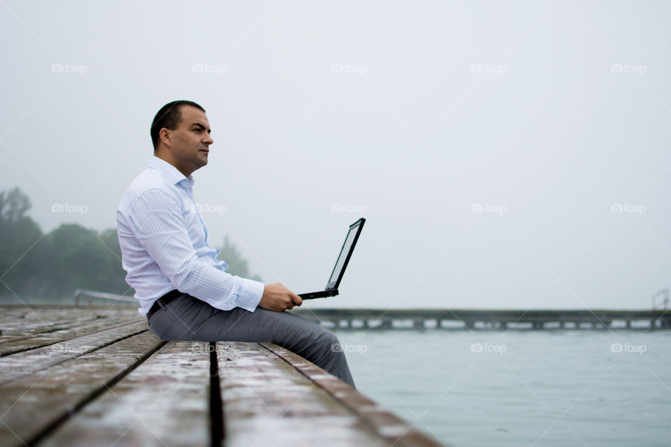 Man on lake dock with laptop