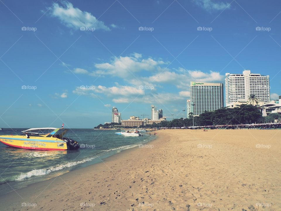 Tourist speedboat anchored on the seashore with tall hotel buildings at the background.