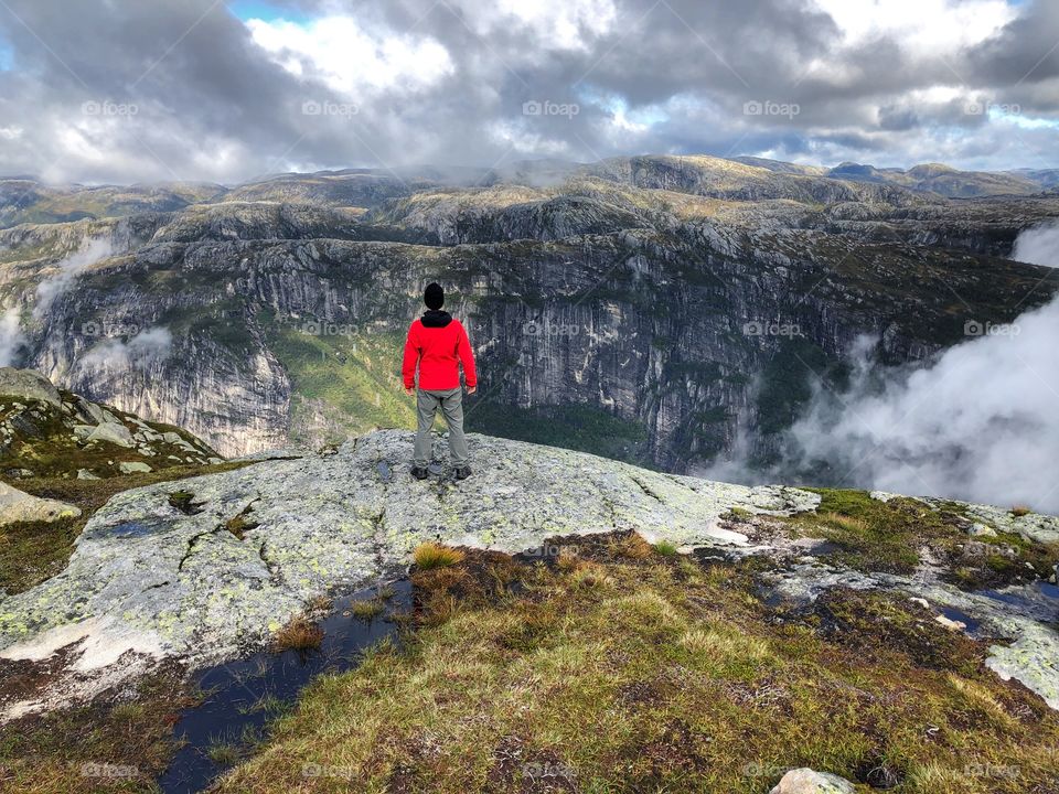 A man standing at the edge of a cliff in Norway