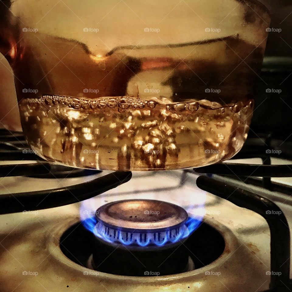 Glass pot of boiling water blue flame gas stove