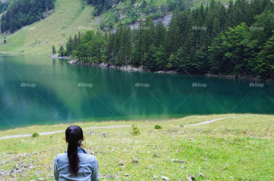 picture behind of the girl sitting with long hair on nature background