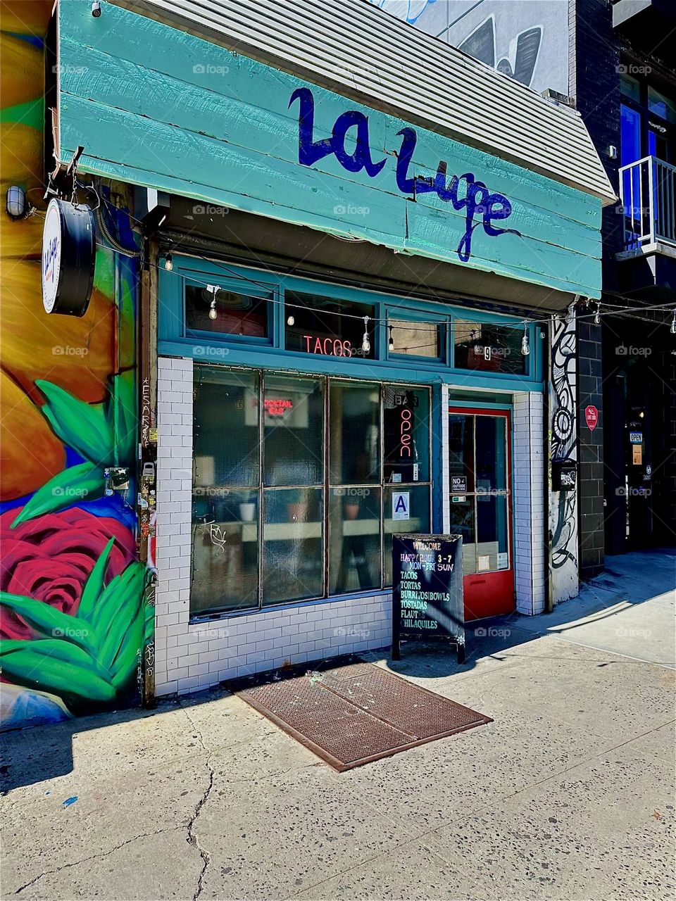 „La Lupe“ is the name of the café right next to the art mural on „Jefferson Street“ off „Broadway“ in „Bushwick“, Brooklyn. 2024. Hypnotic Productions