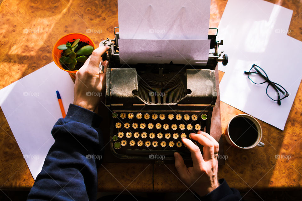A young writer is writing a new book on an old typewriter.