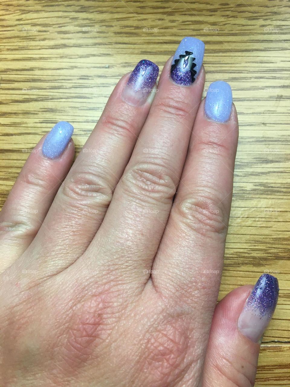 Freshly manicured middle aged lady hand, with shiny purple glittered long gel nails