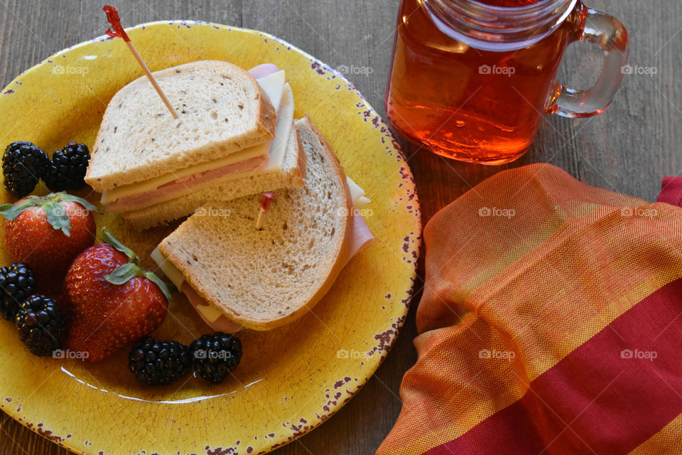 Ham and cheese sandwich with fruit and a glass of juice