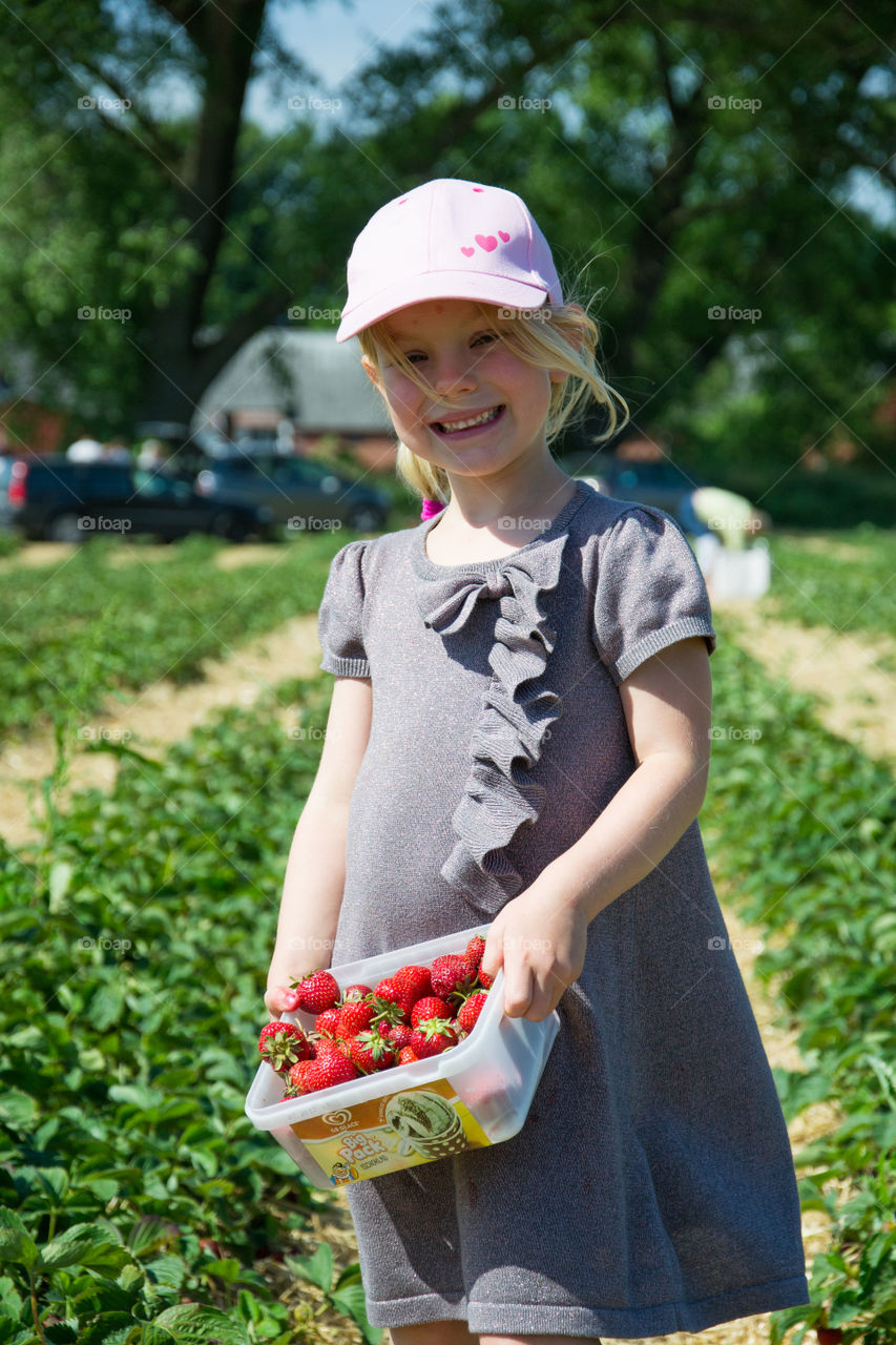 Girl holding fresh strawberries in plastic box