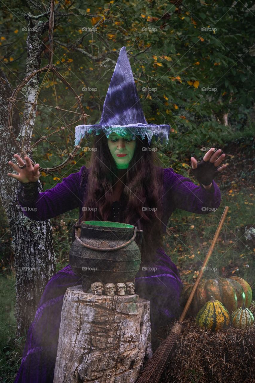 A purple clad witch, casting spells over her cauldron deep in the woods