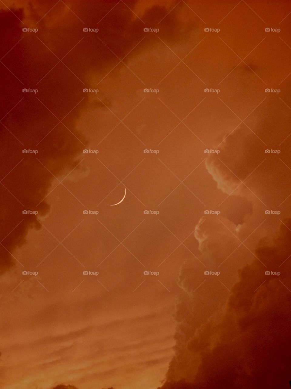 Beautiful red clouds in the evening with a sliver of the moon in the background.