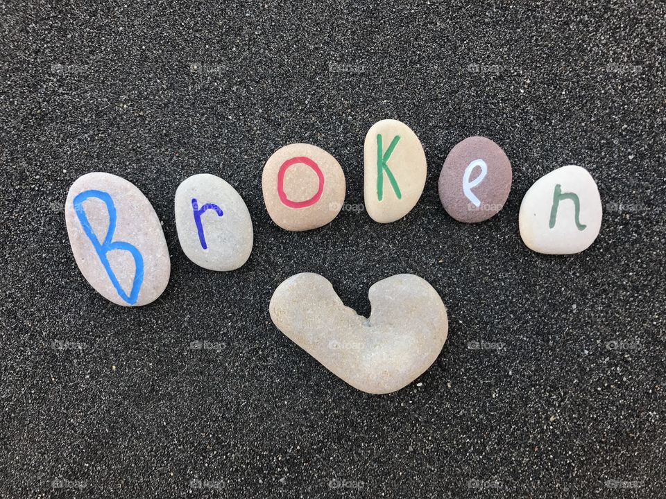 Broken love conceptual stones composition over black volcanic sand 