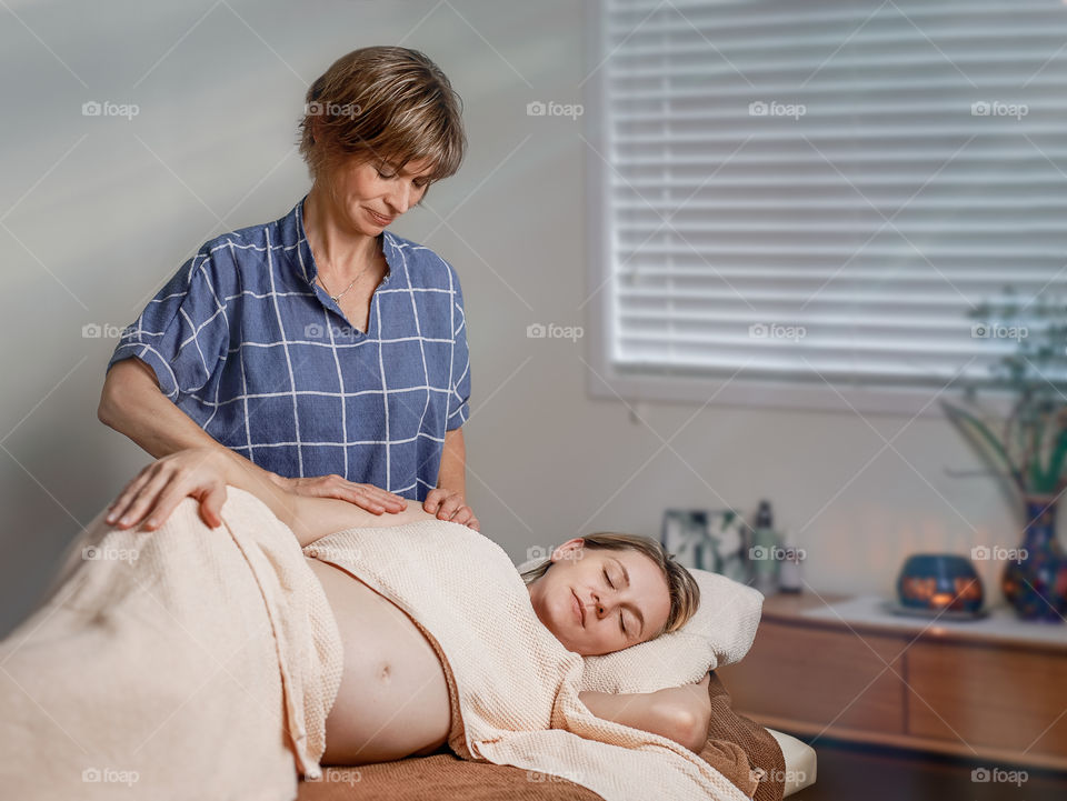 a pregnant woman is getting massage