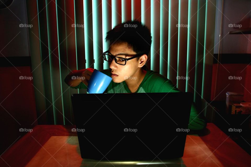 teenager drinking coffee in front of a laptop computer