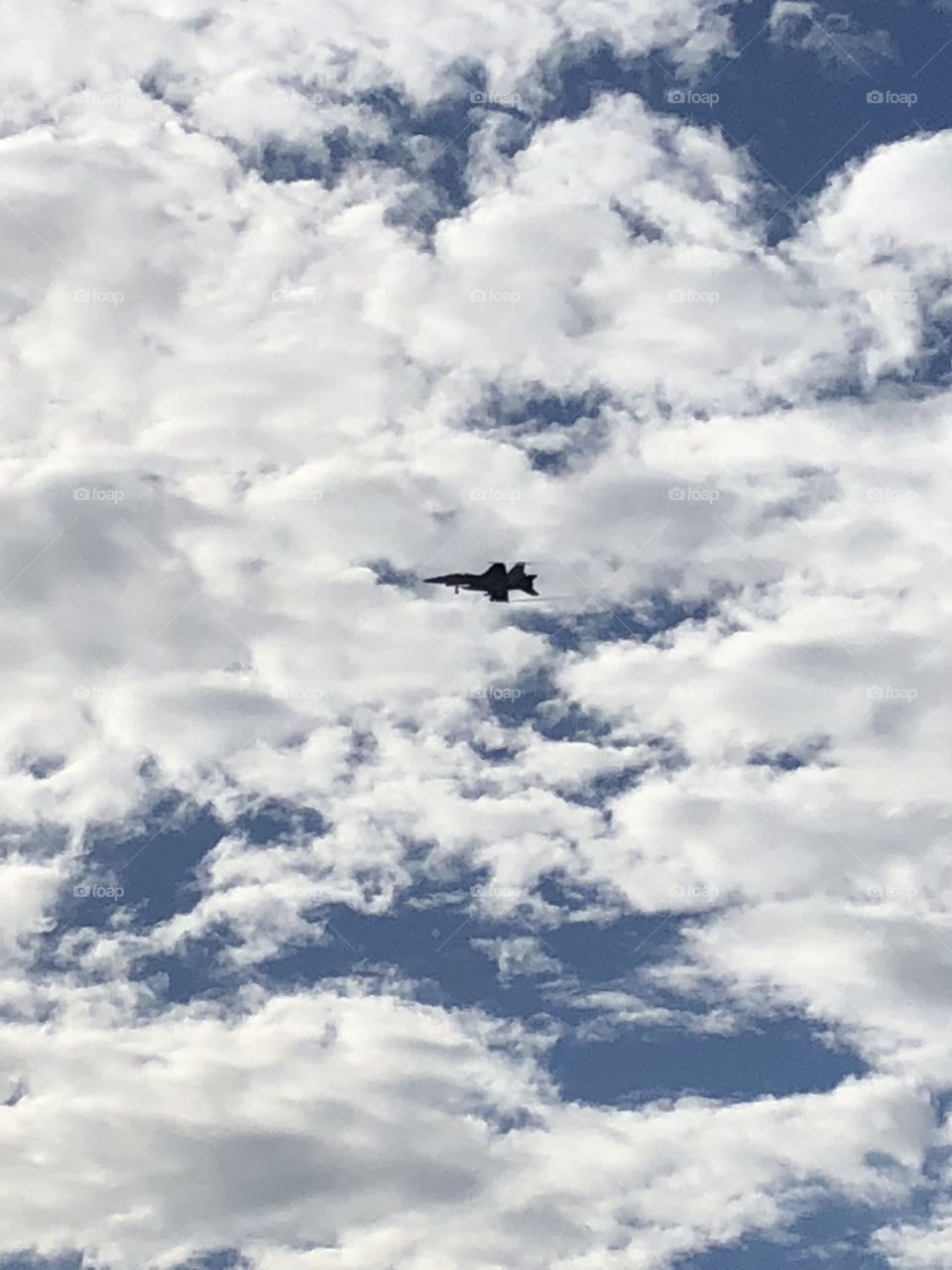 Jet flying through cloudy blue skies