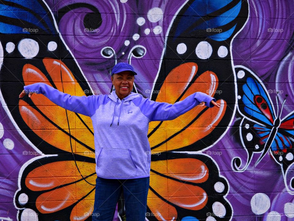 Color Purple - standing in front of the purple mural with her arms outstretched to become one with the art