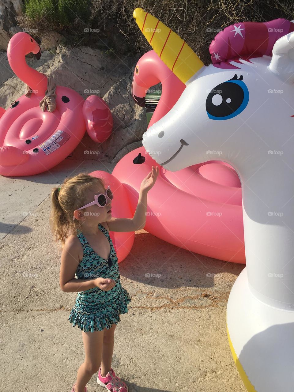 Girl at the beach playing with a unicorn floaty.