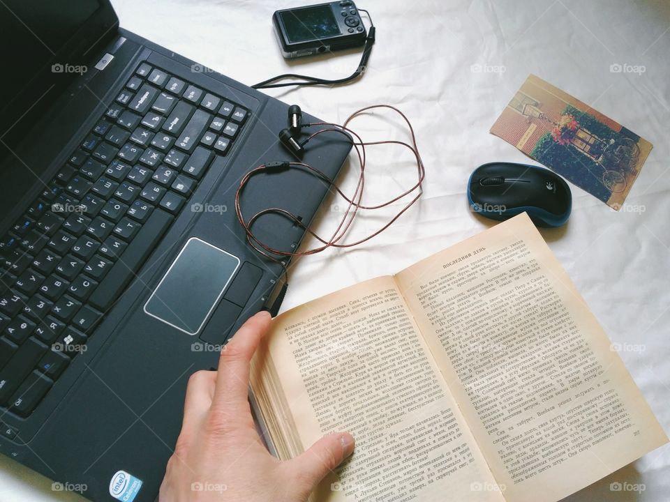 Laptop, book, headphones, computer mouse and camera are on the table