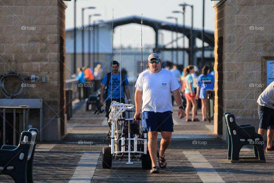 Man walking with the fishing equipment at the sea port