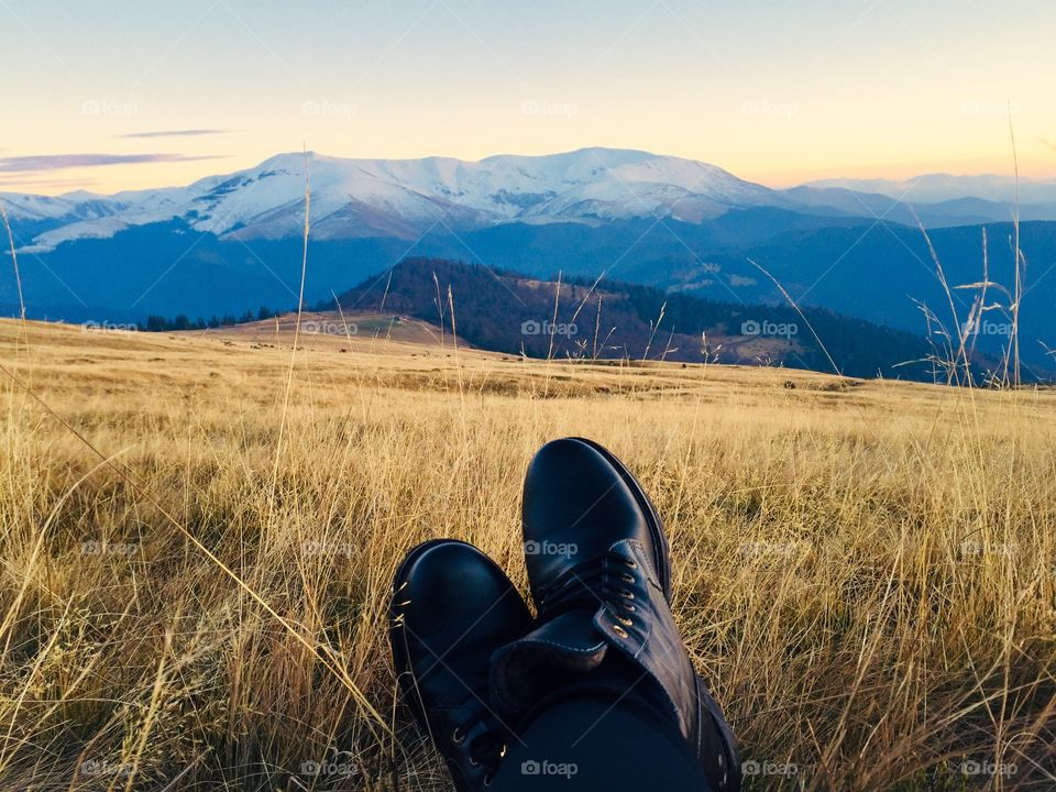 Black boots and mountains covered in snow in the background 
