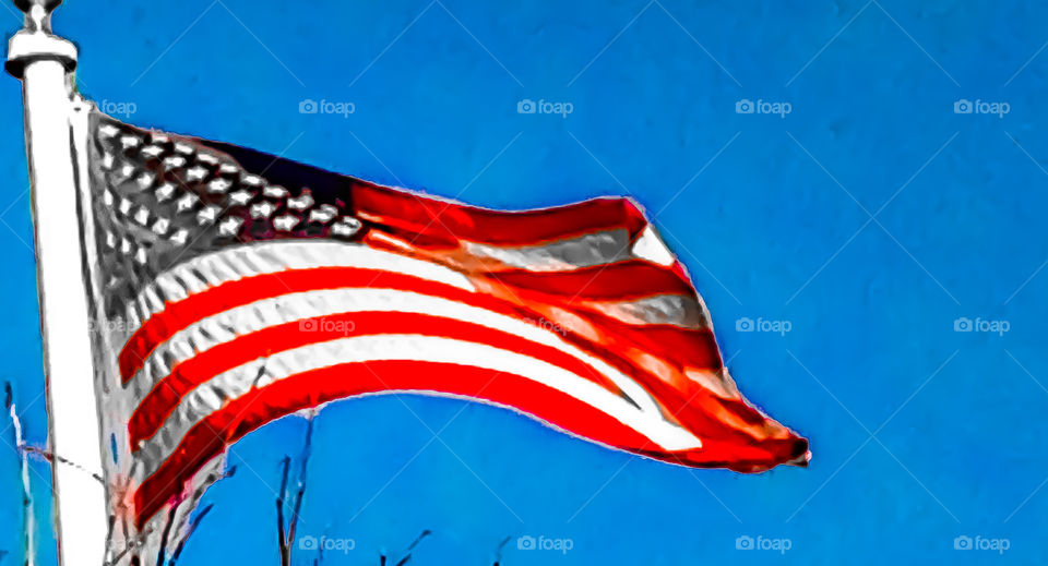 O say can you see . . . The American flag proudly waving during a windy day with a stunning blue sky as the backdrop. 