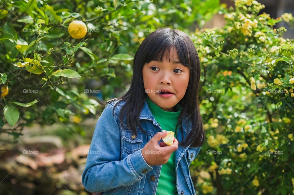 Time to enjoy the fruits of spring season. A candid portrait shot of a little girl eating fruits.