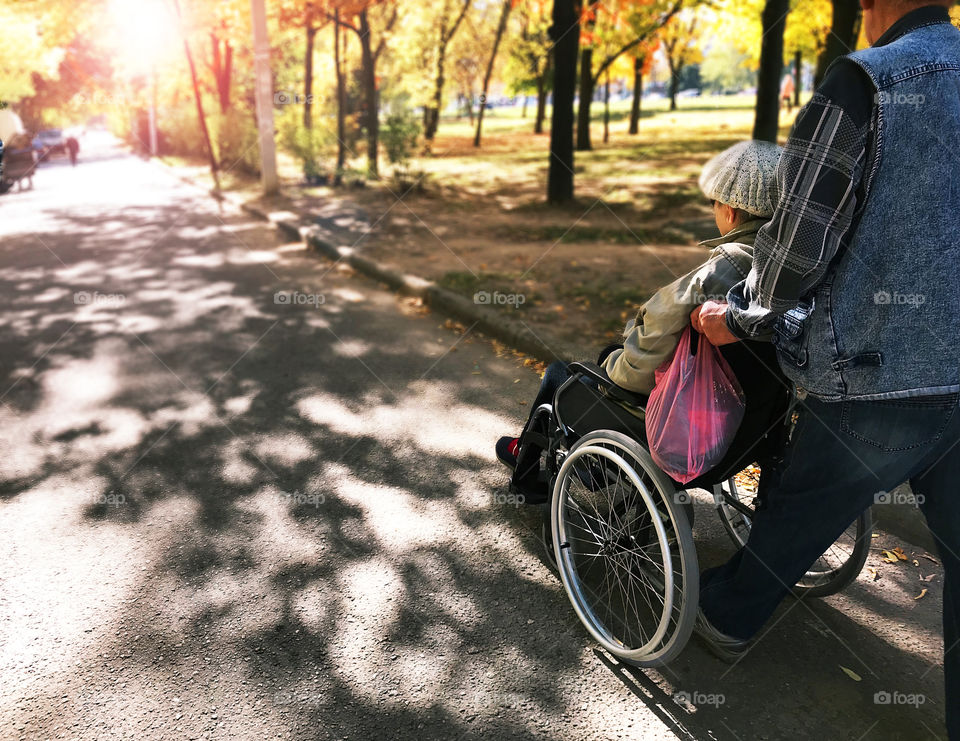 Traveling through the sunny autumn city road in wheelchair