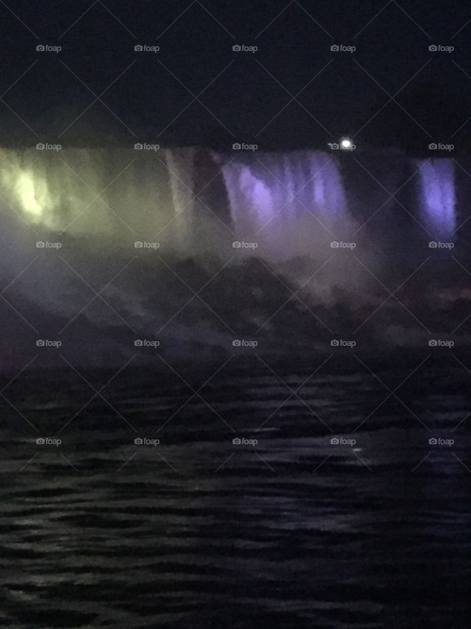 Niagara Falls light up beautifully on a dark night. The multicolored lights catch the mist and dance across the water. 
