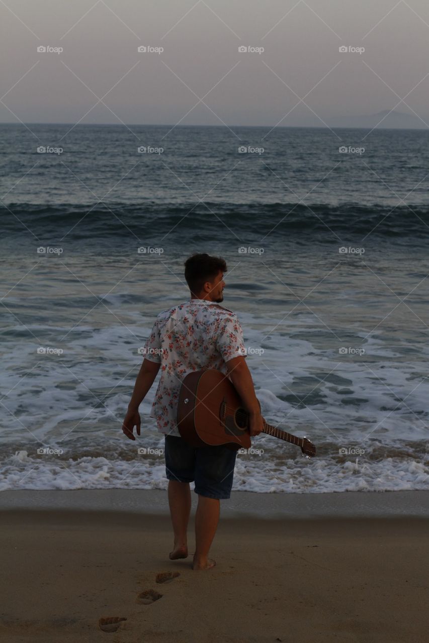 Boy on the beach with his guitar