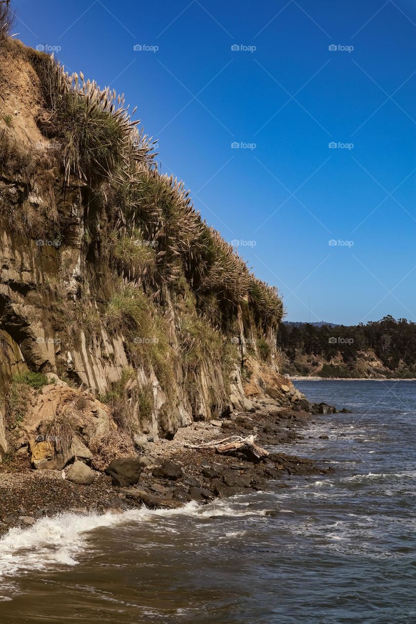 View of the cliffs in Capitola California on a crystal clear day with a clear blue sky as the cold Pacific Ocean waters cool the air 