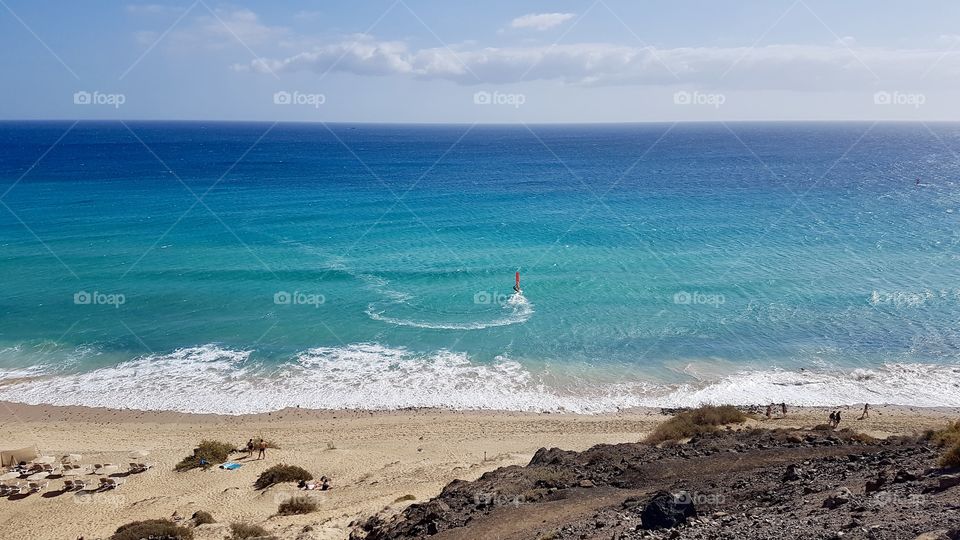 Windsurfer in action on beautiful turquoise blue sea in fair weather, Fuerteventura Canary Islands Spain - vindsurfare blått turkost hav soligt, semester Kanarieöarna 