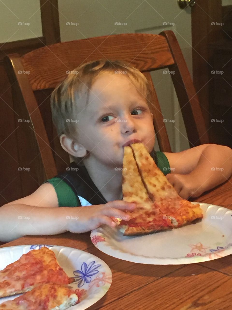 Close-up of a little boy eating pizza at home