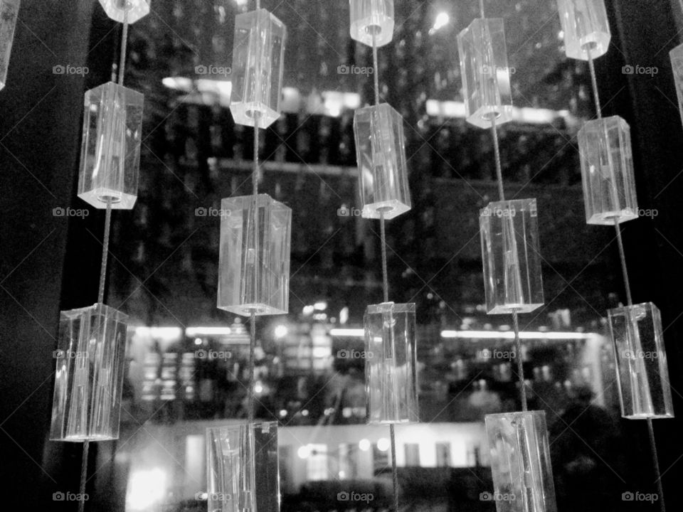 Reflections on a window covered by a beaded acrylic curtain in black and white.