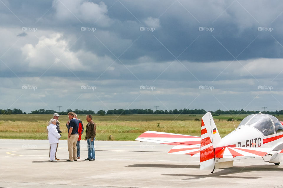 Personengruppe auf dem Flugfeld, daneben ein Kleinflugzeug