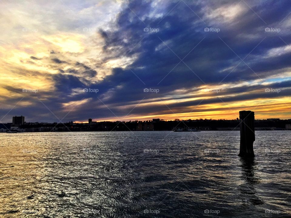 Sunset on the Hudson River, New York City . Sunset on the Hudson River, New York City. Blue and golden sky with light streaks.
