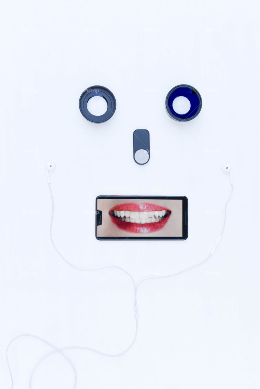 Flat lay of assorted technology gadgets arranged to make a face