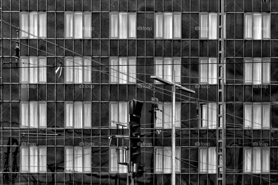 Black and white photo of a monotonous building with windows and white curtains