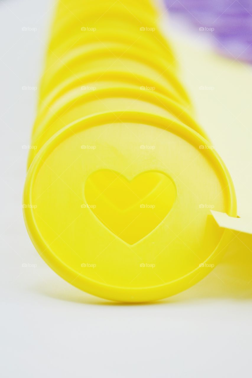 Closeup of yellow discbound disc with heart-shaped cut-out  for discbound planner against white background