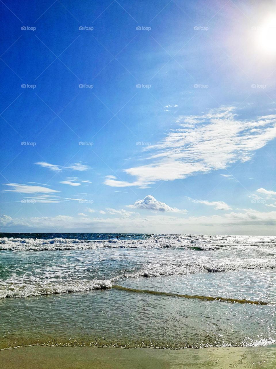 A beautiful sunny day with beautiful blue sky and the waves crashing on the shore at Indian Rocks Beach.