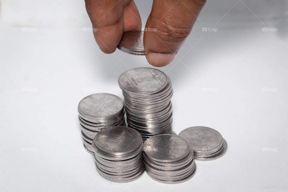 A businessman putting coins over a stack of coins. Financial, economy, investment and savings concept. Banking and exchange object. Close up view.