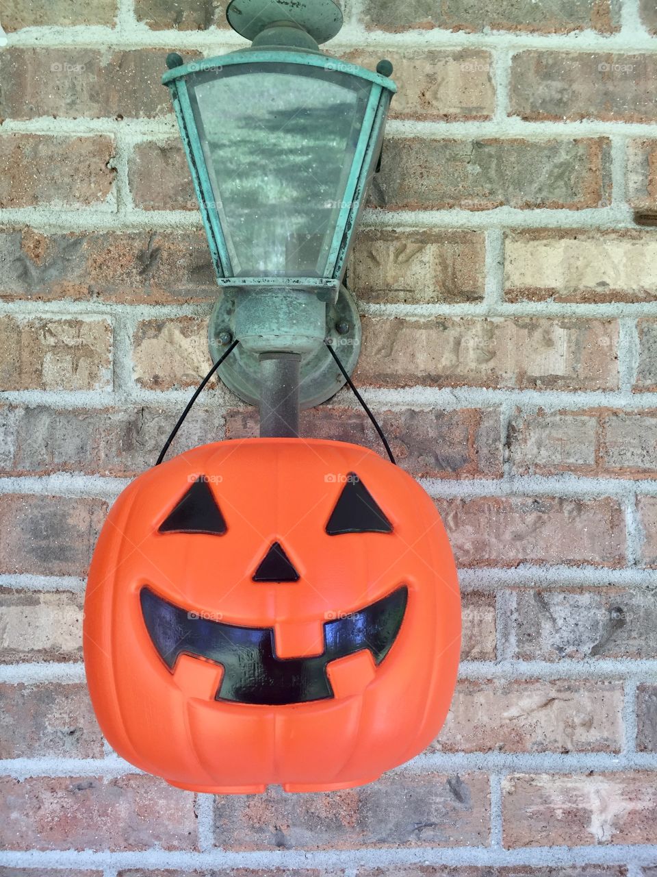 Plastic pumpkin on a brick wall on a light fixture Halloween decoration