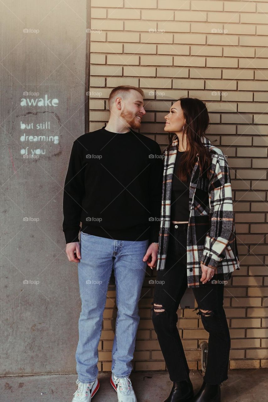 engaged couple with cute saying on wall.