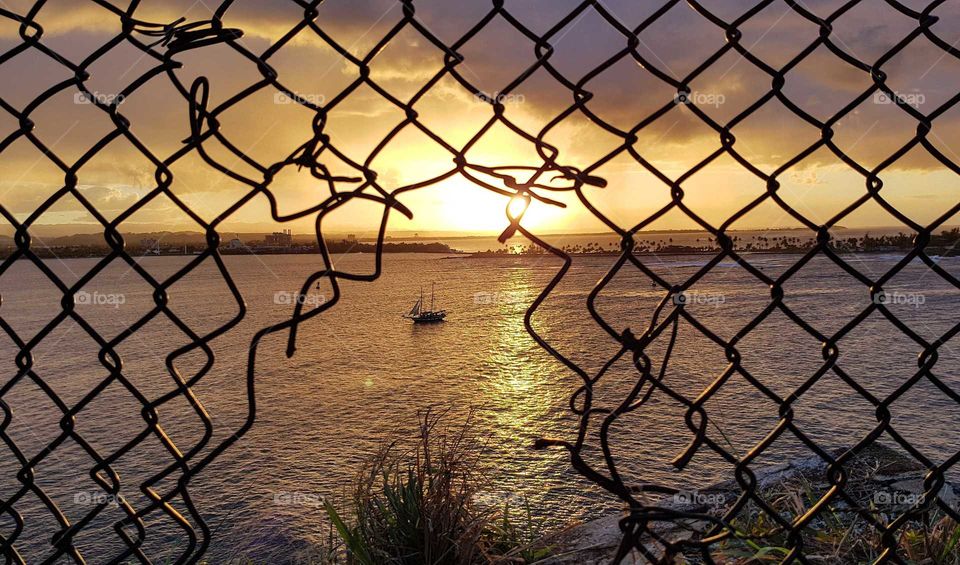 Sunset over the sea through a hole in a grid