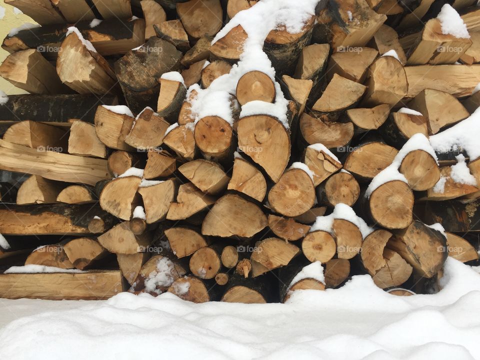 Pile of cut firewoods covered in snow