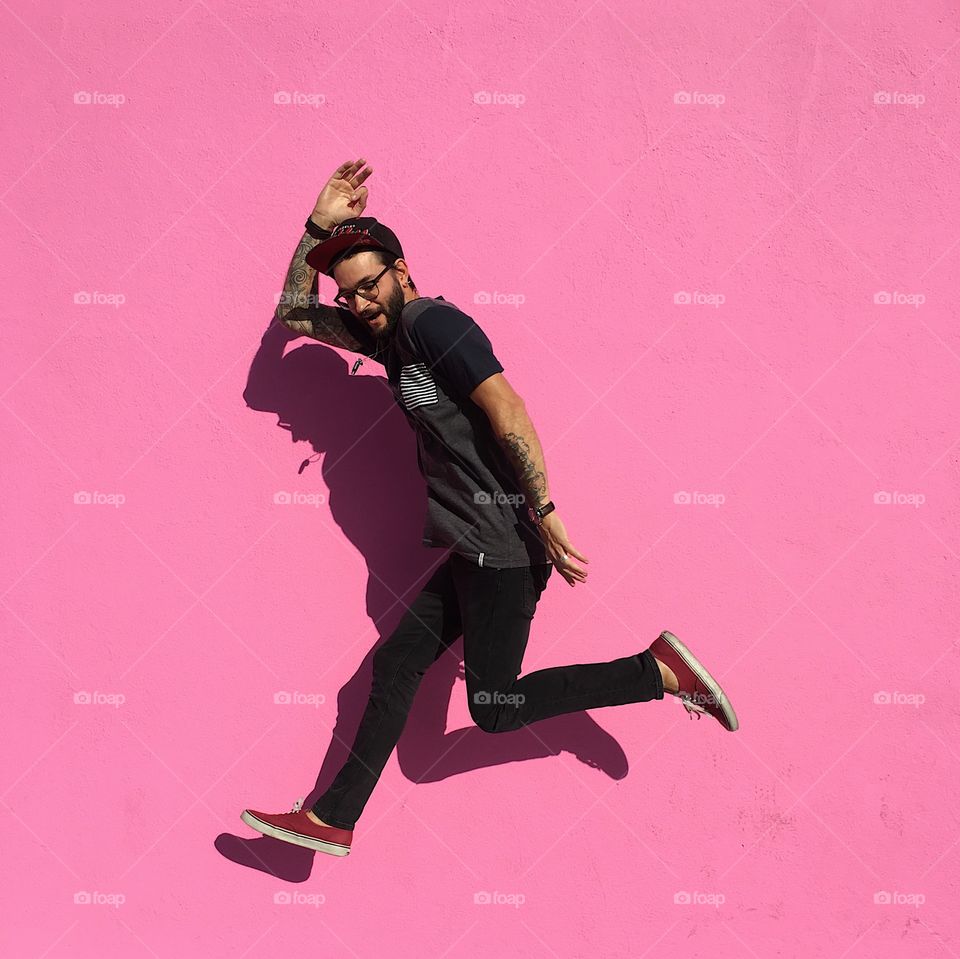Jumping against a pink wall. 